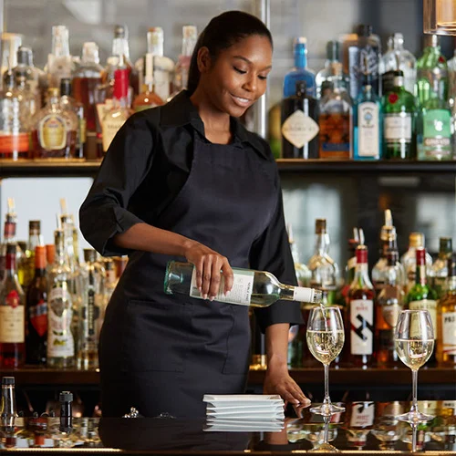 female-bartender-at-upscale-bar-pouring-white-wine-from-bottle-into-glass